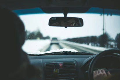 Driving in snowy conditions with a car ahead of them on the road.