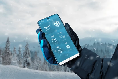 A person holding a phone showing the weather forecast.