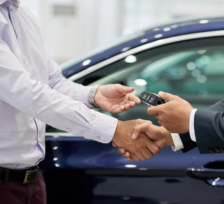 people shaking hands exchanging new car keys