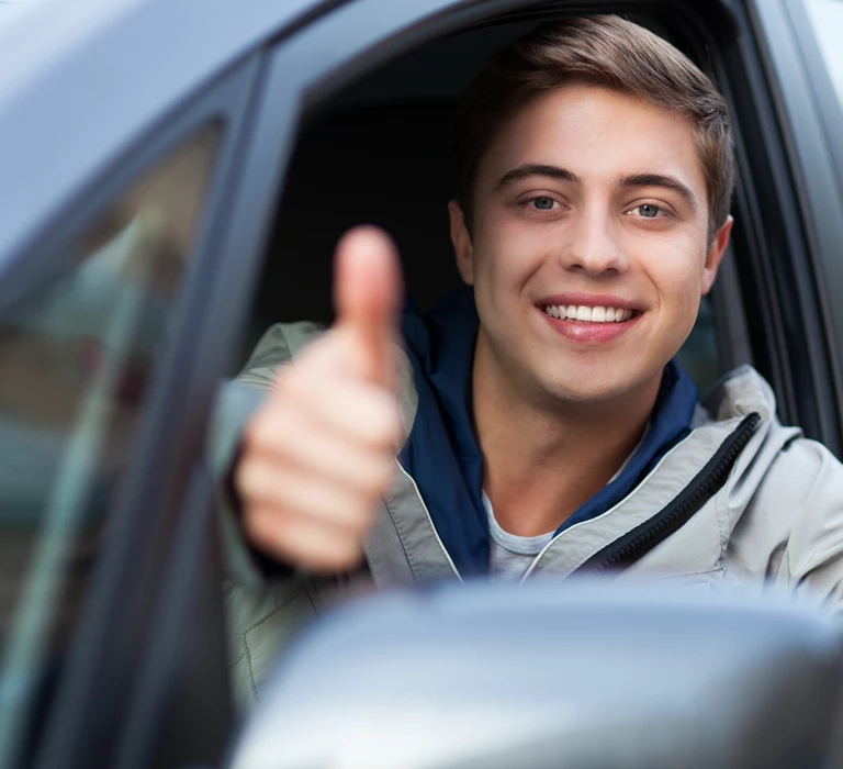 A young driver leaning out of the car giving a thumbs up. Car Leasing For Young Drivers : What's The Catch?